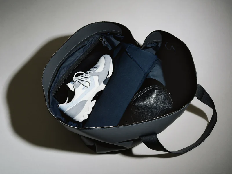 Interno ordinato di una sacca con vano scarpe, maglia piegata e taschino